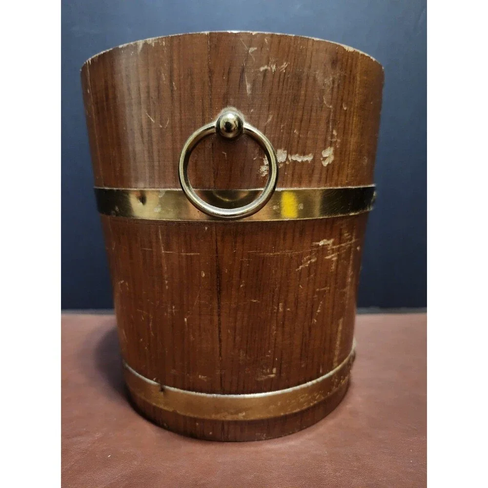 This is a vintage wood and brass barrel-style ice bucket typically measuring...